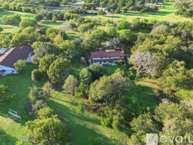 A house with a red roof is surrounded by trees.