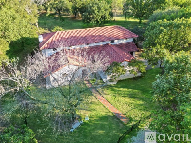 A house with a red roof is surrounded by trees and grass.
