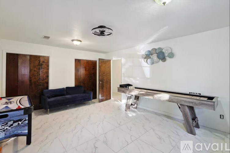 A pool table is in the middle of a room with a couch and a TV.