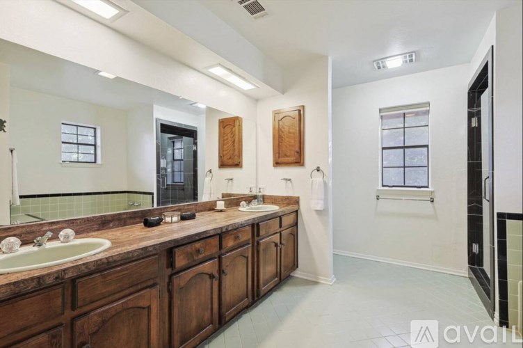 A bathroom with a large mirror, two sinks, and wooden cabinets.