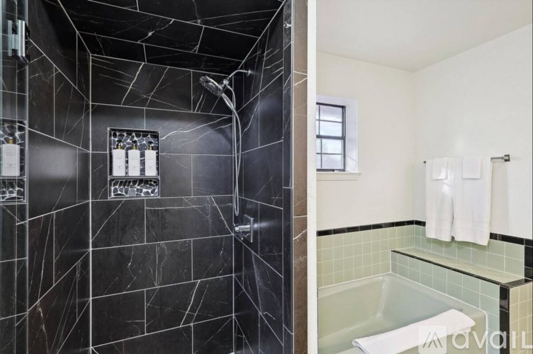 A black and white bathroom with a glass shower and a white towel hanging on the wall.