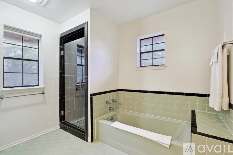 A bathroom with a glass shower door and a white bathtub.