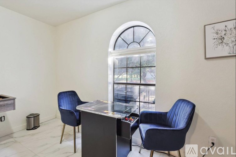 A room with a desk and two chairs in front of a window.
