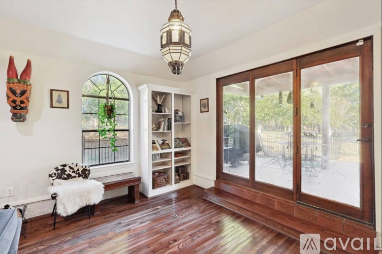 A room with a wooden floor and a white bench with a black and white pillow.