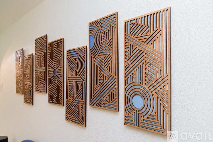 A series of five wooden panels with intricate designs are displayed on a wall.