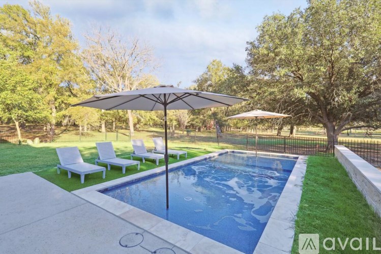 A pool surrounded by a white fence and trees.