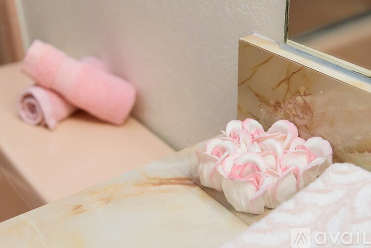 A pink towel is rolled up and placed on a marble countertop.