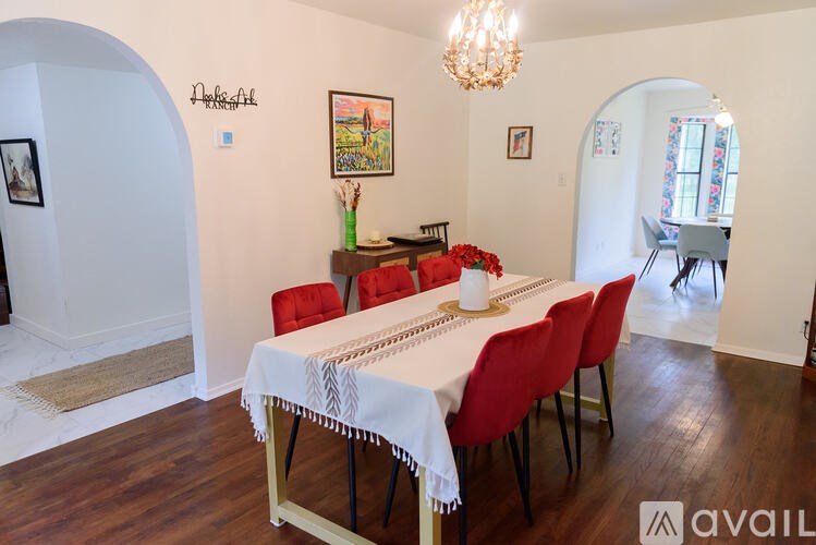 A dining room with a white table and red chairs.