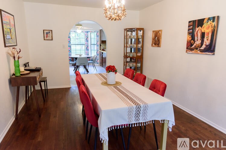 A dining room with a white table and red chairs.