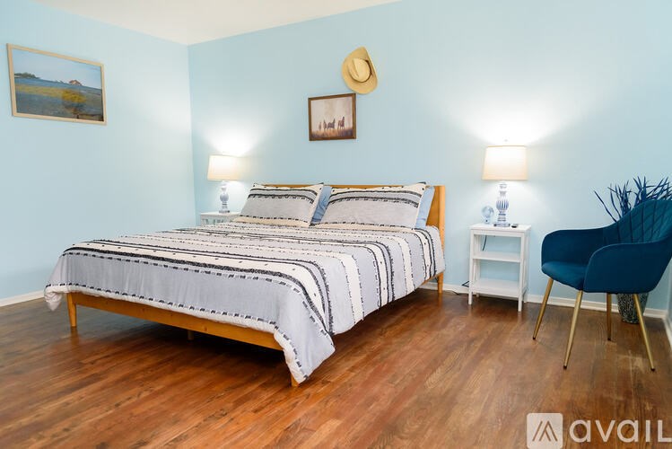 A bedroom with a bed, two lamps, and a chair.