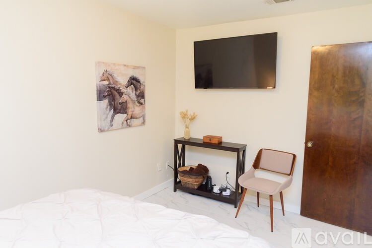 A bedroom with a bed, chair, and painting on the wall.