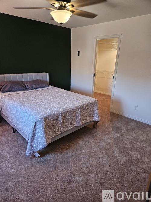 A bedroom with a bed and a ceiling fan.