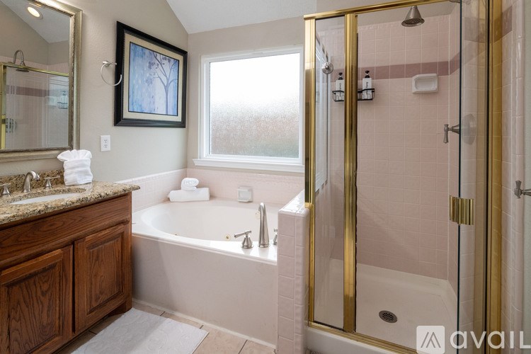 A bathroom with a gold shower door and a white tub.
