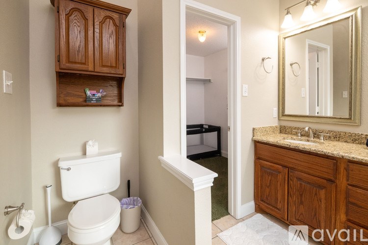 A bathroom with a toilet, sink, and wooden cabinets.