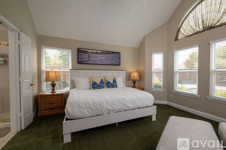 A bedroom with a large bed, a flat screen TV, and two lamps.