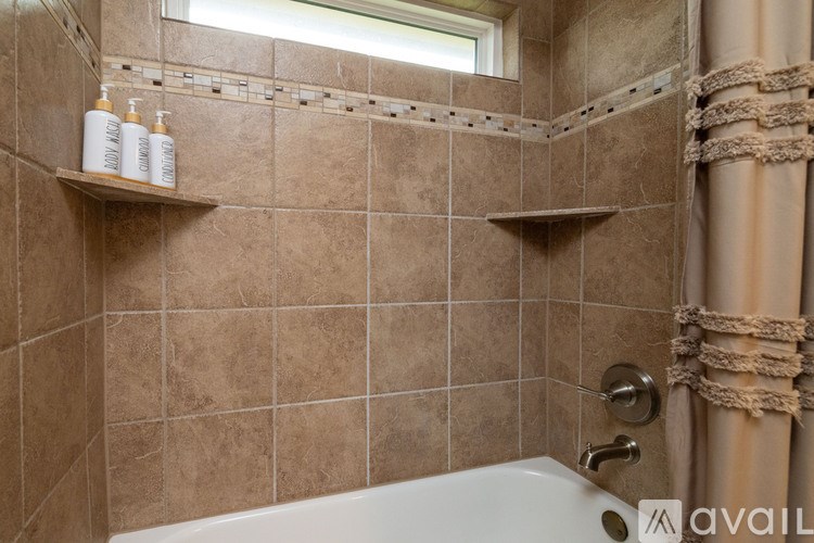 A bathroom with brown tiles and a white tub.