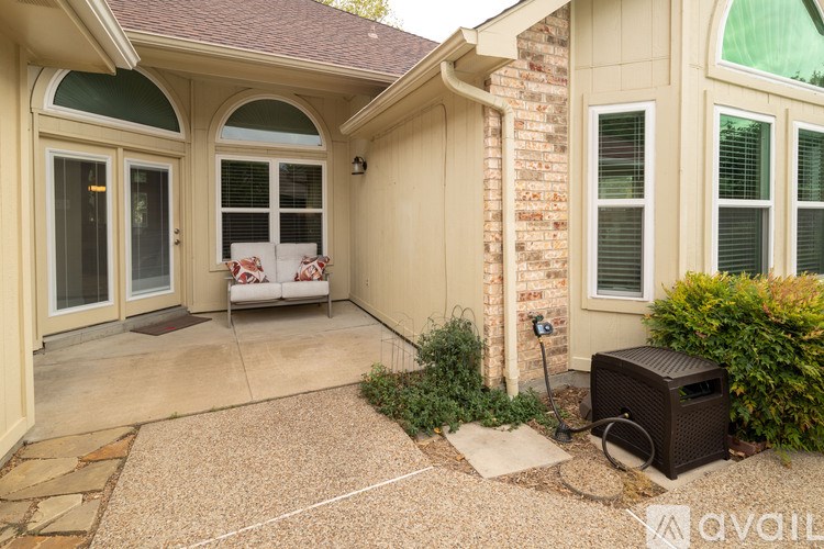 A patio area with a couch, table, and a wall with a brick pattern.