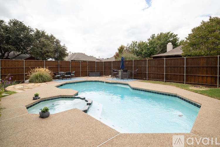 A pool with a hot tub and a fence surrounding it.
