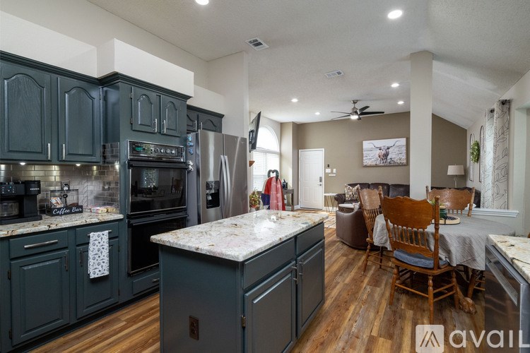 A kitchen with dark green cabinets and a marble countertop.