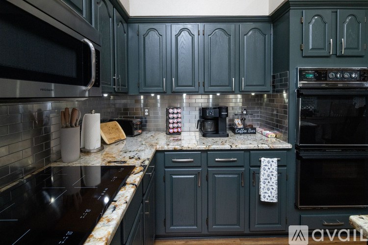 A kitchen with dark green cabinets and a black stove top.