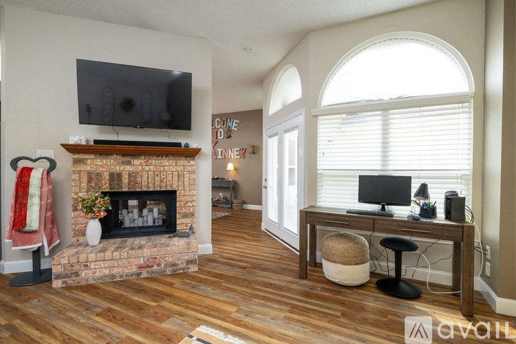 A living room with a fireplace and a television mounted above it.