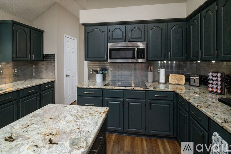 A kitchen with dark green cabinets and a granite countertop.