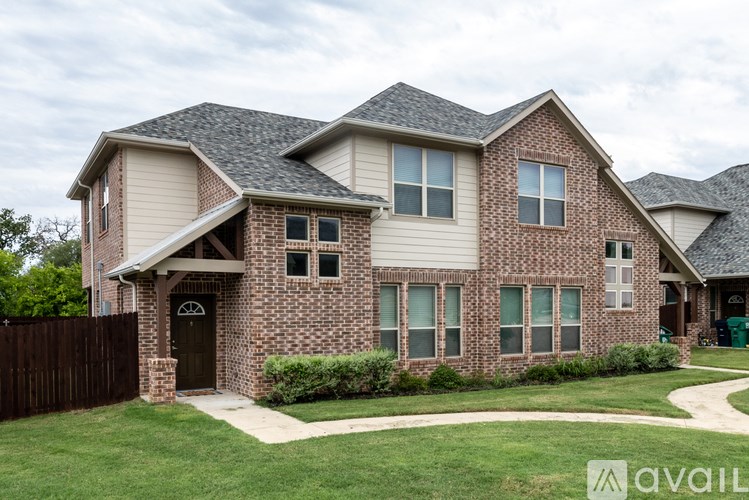 A brick house with a brown door and a small porch.