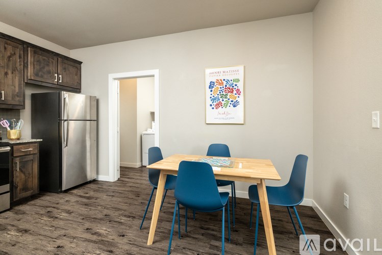 A kitchen with a refrigerator, cabinets, and a dining table with chairs.