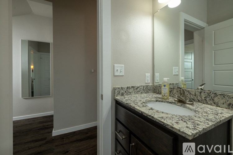 A bathroom with a granite countertop and a large mirror.