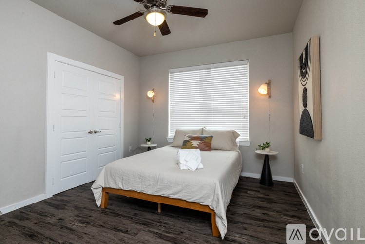 A bedroom with a bed, a ceiling fan, and a painting on the wall.