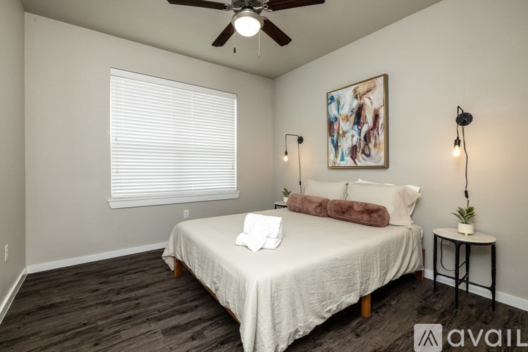 A bedroom with a bed, a ceiling fan, and a painting on the wall.