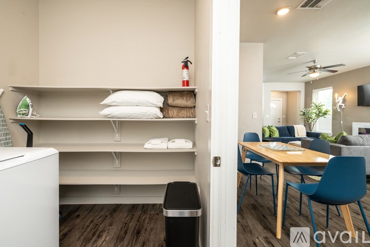 A kitchen with a white fridge and a dining table with chairs.