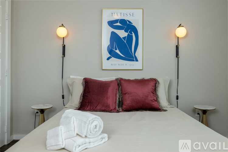 A bedroom with a bed, two lamps, and a framed picture on the wall.