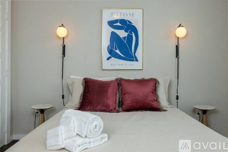 A bedroom with a bed, two lamps, and a framed picture on the wall.