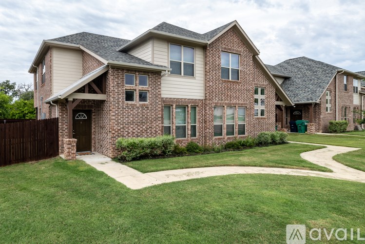 A house with a brown brick facade and a green lawn in front.