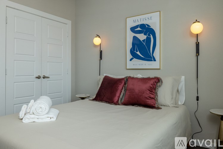 A bedroom with a bed, pillows, and a poster on the wall.