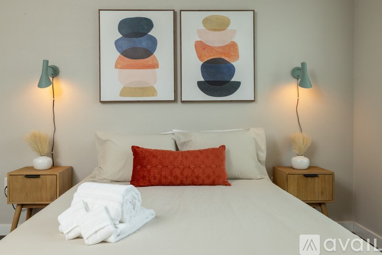 A bedroom with a bed, two nightstands, and two framed artworks on the wall.