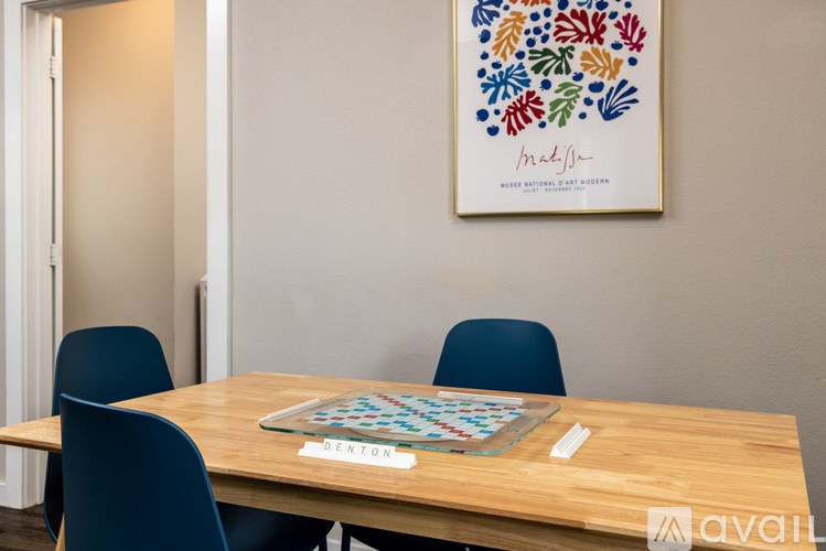 A wooden table with a puzzle on it and a framed picture of flowers on the wall.