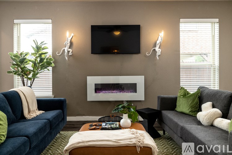 A living room with a blue couch, a white wall, and a flat screen TV mounted above a fireplace.
