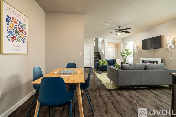 A living room with a grey couch and a dining table with blue chairs.