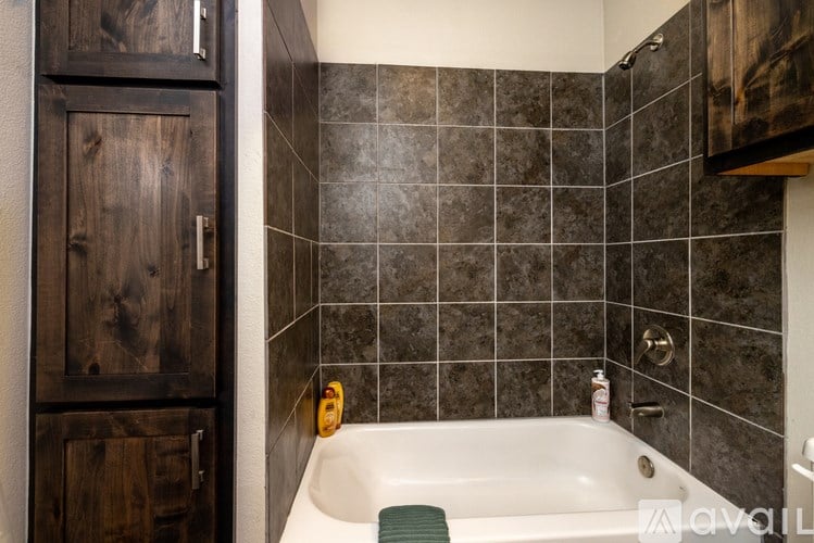 A bathroom with a white tub and wooden cabinets.