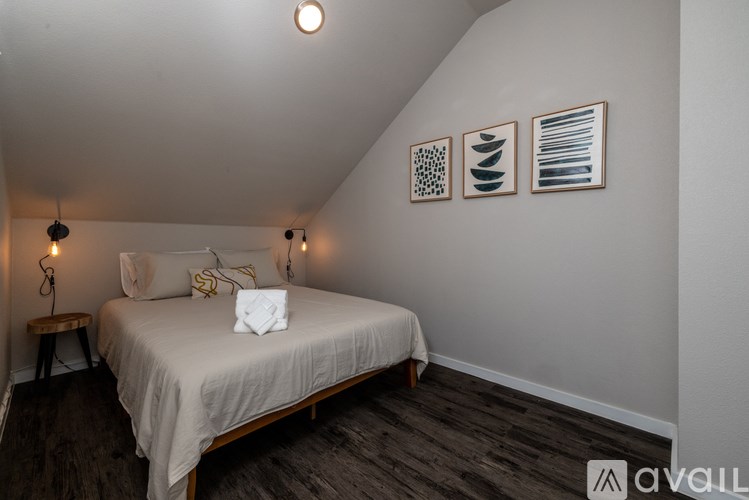 A bedroom with a bed, pillows, and three framed pictures on the wall.