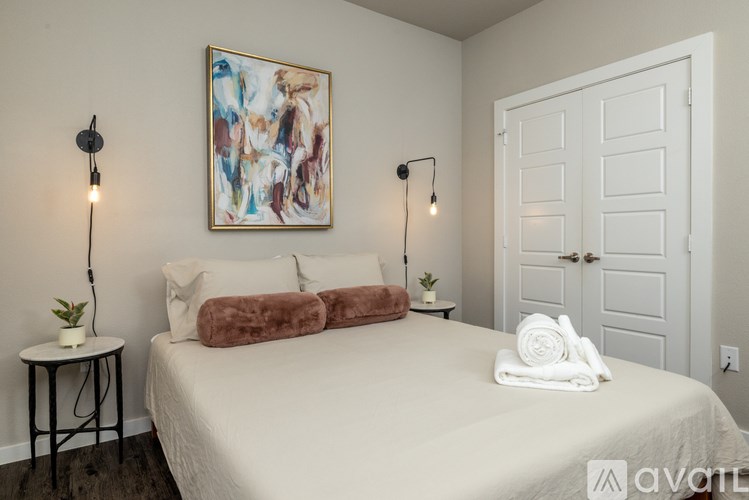 A bedroom with a large bed, a painting on the wall, and a door.