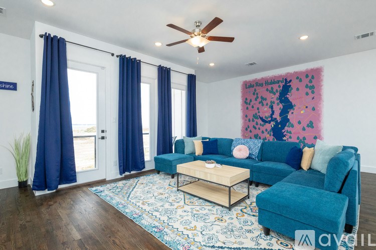 A living room with a blue couch and a rug.
