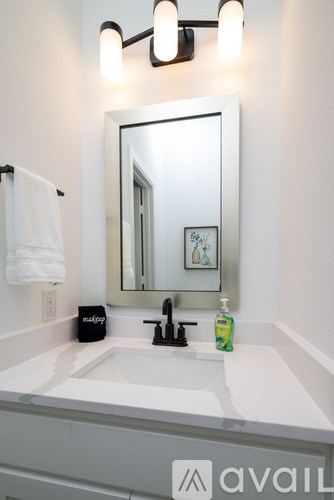 A bathroom sink with a mirror above it and a bottle of lotion on the counter.