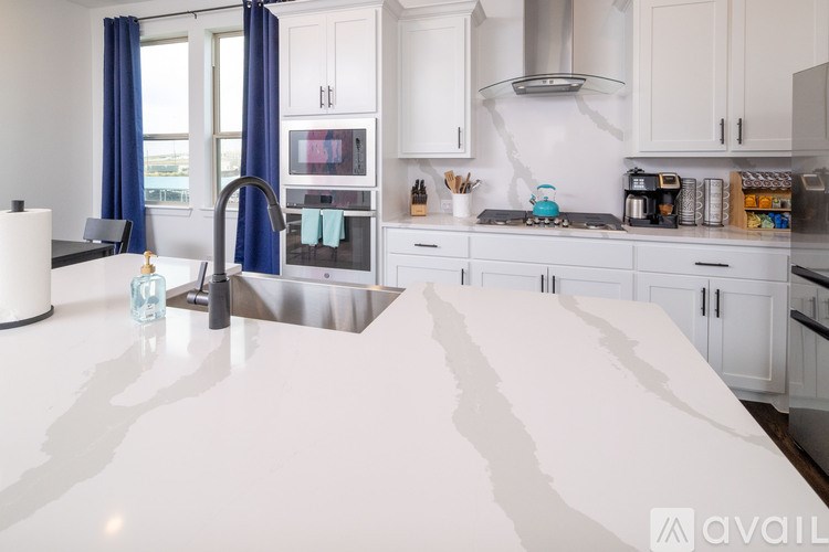 A kitchen with white countertops and blue curtains.