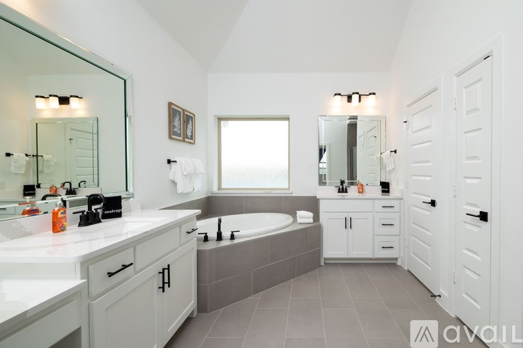 A bathroom with a large mirror, a bathtub, and a sink.