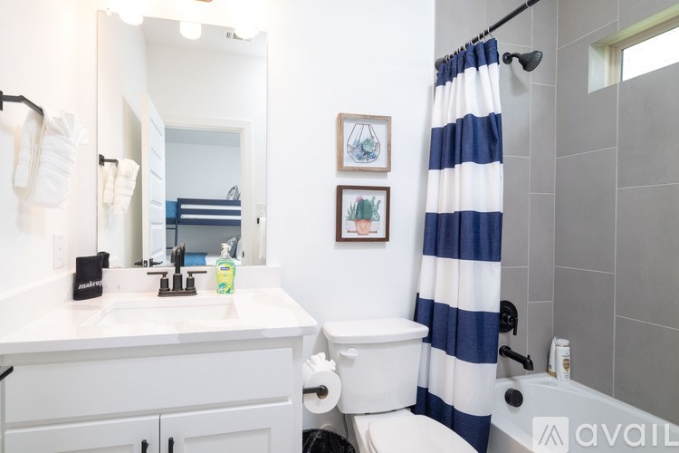 A bathroom with a white counter and a blue and white striped shower curtain.
