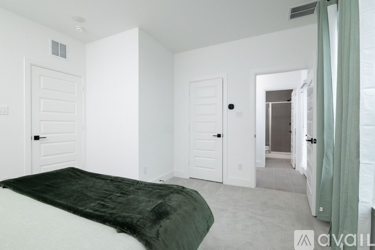 A bedroom with a bed covered in a green blanket and white walls.