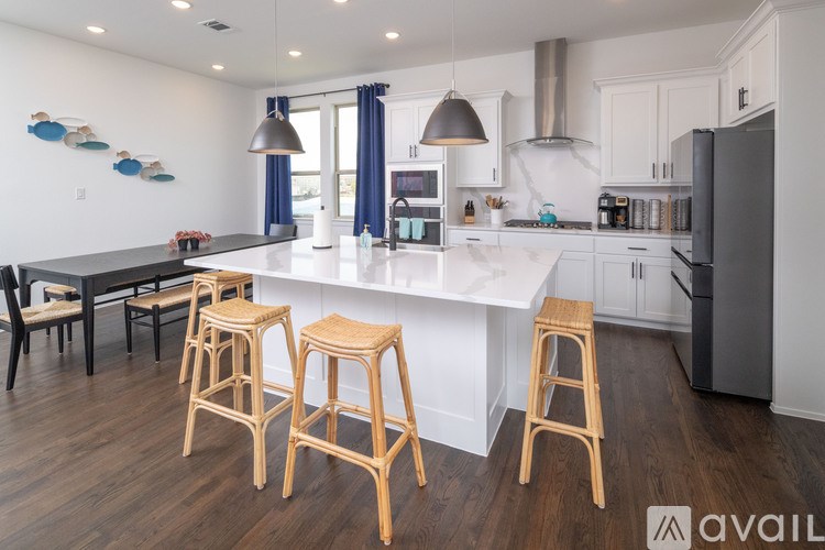 A kitchen with a white island and wooden stools.